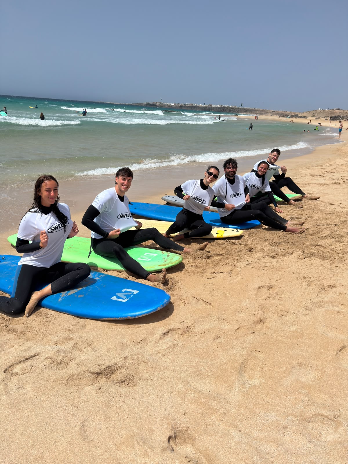 Small SWELL group on the beach with surfboards